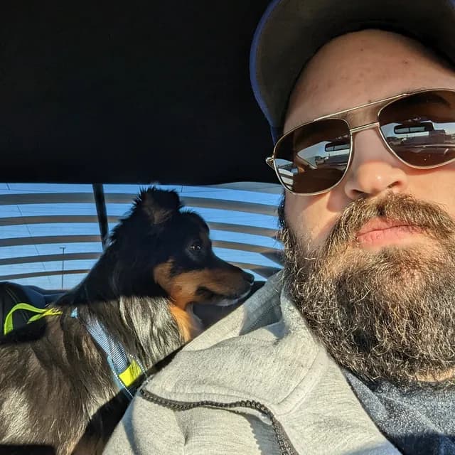 Mark in the driver's seat with his dog leaning in from the passenger side